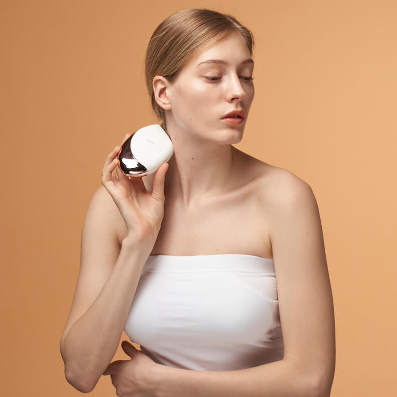 Woman using Aalok FITSERA on her neck against a beige background