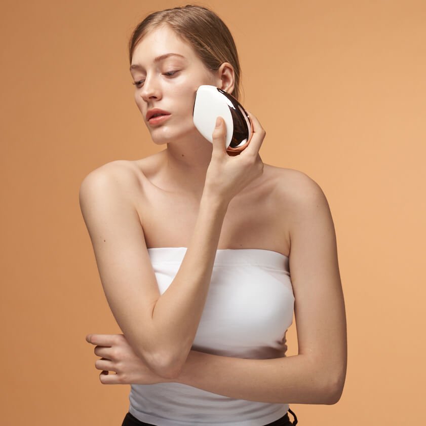 Woman holding Aalok FITSERA against her cheek against an orange background