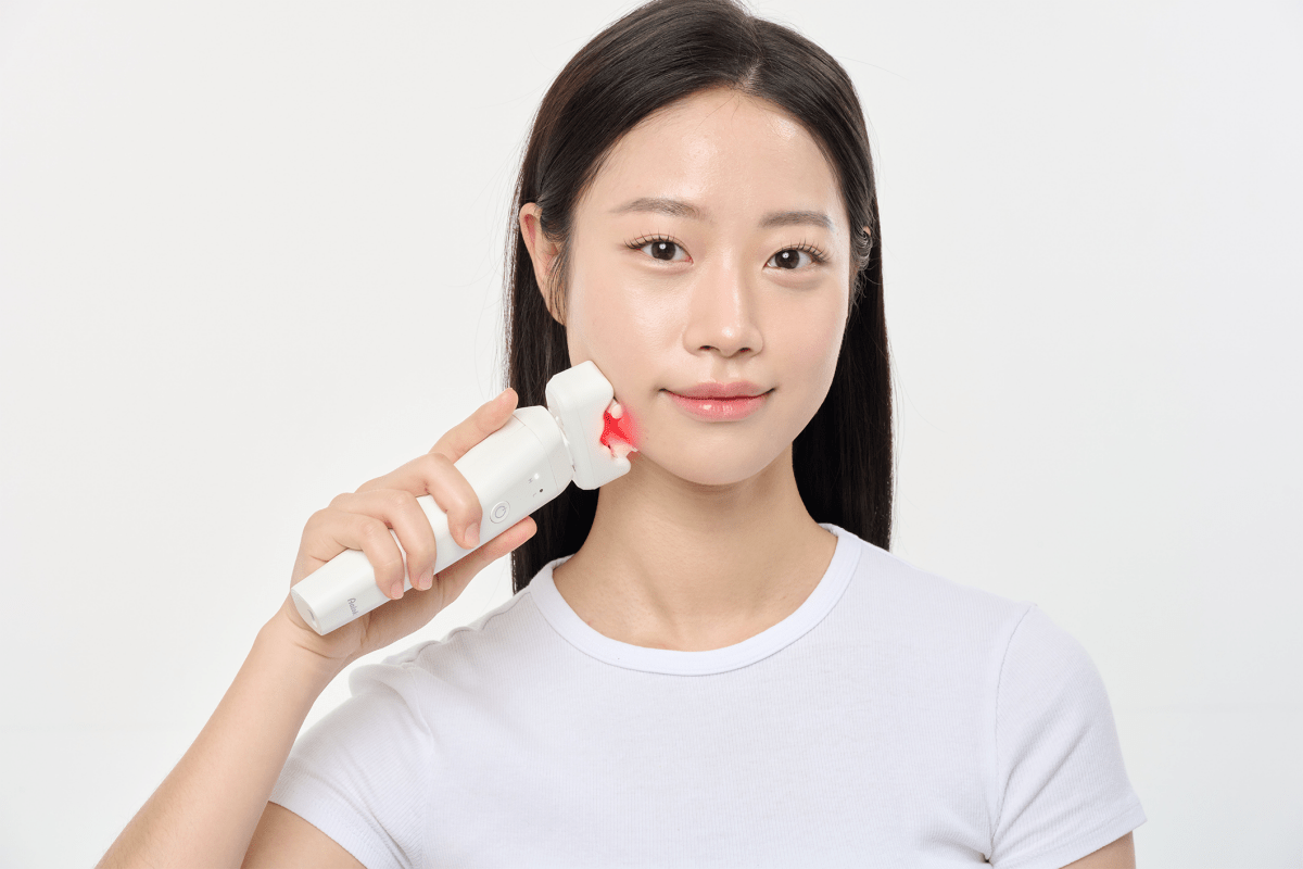 Woman using an Aalok ULTRA Olla on her jaw against a plain background