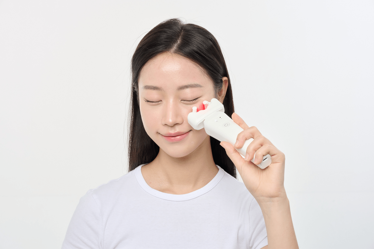 Woman using an Aalok ULTRA Olla under her eye with a white background