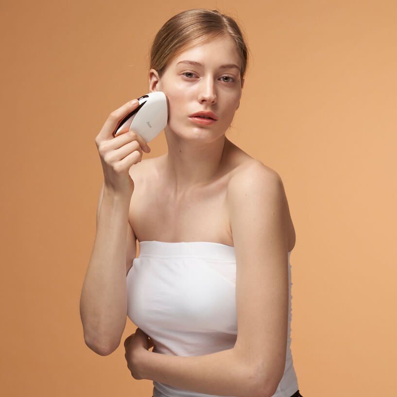 Woman using Aalok FITSERA on her face against an orange background
