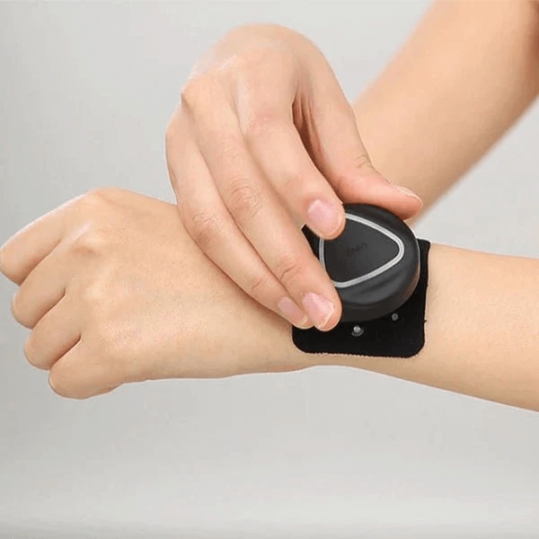 A person applying an Aalok Patch to their wrist on a gray background