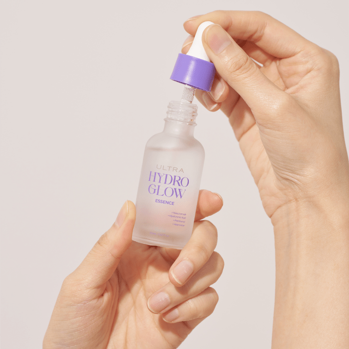 Hand holding a bottle of Aalok Ultra Hydro Glow essence against a light background