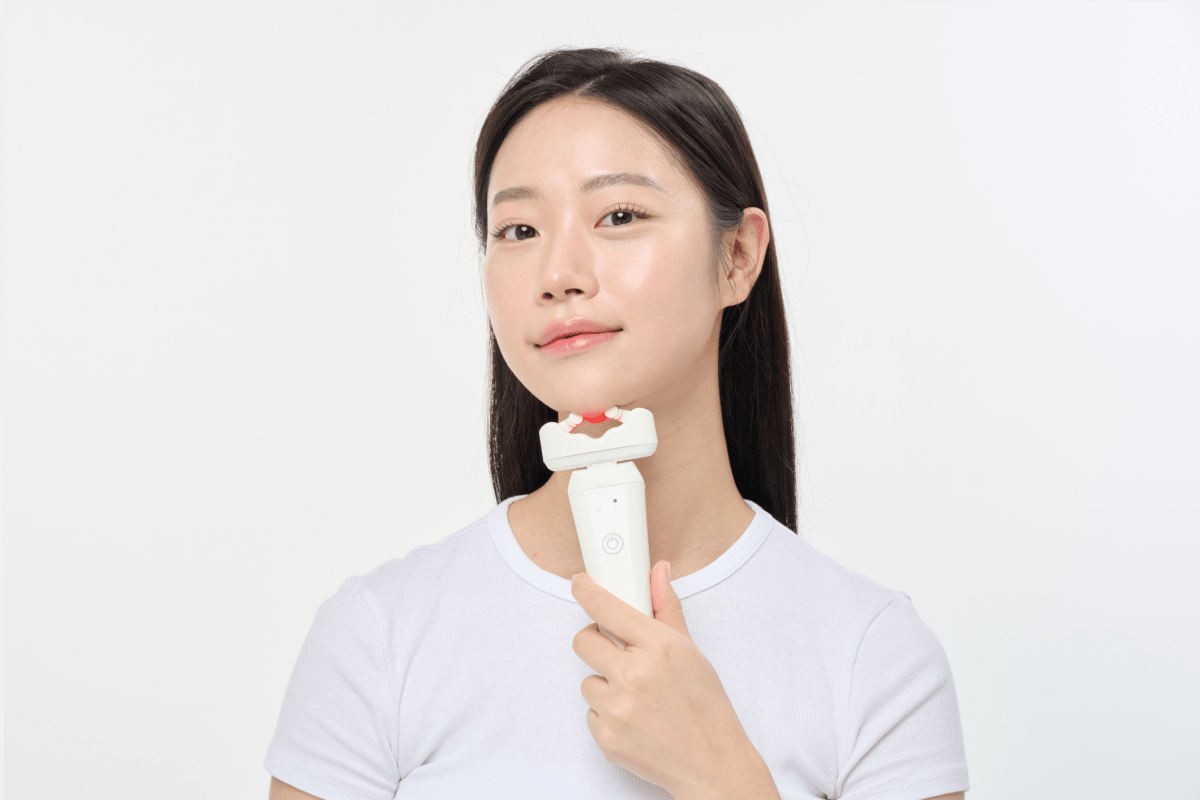 Woman using an Aalok ULTRA Olla on her chin against a plain background